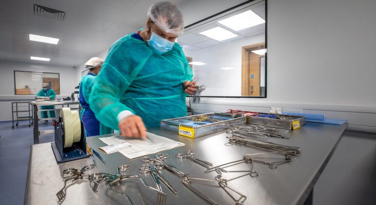A man setting up and checking the sanitation of surgical tools.